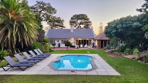 A backyard with a swimming pool, lounge chairs, and a house with a patio. - KaapsePracht (Cape Town)