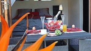 A dining area with a table set for two, a basket of bread, a glass of juice, and a plate of food. - KaapsePracht (Cape Town)