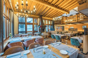 A restaurant with wooden beams, large windows, and multiple dining tables set with tableware. - Beau-Rivage (Zermatt)