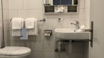 Ein modernes Badezimmer mit Toilette, Waschbecken und Spiegel.
