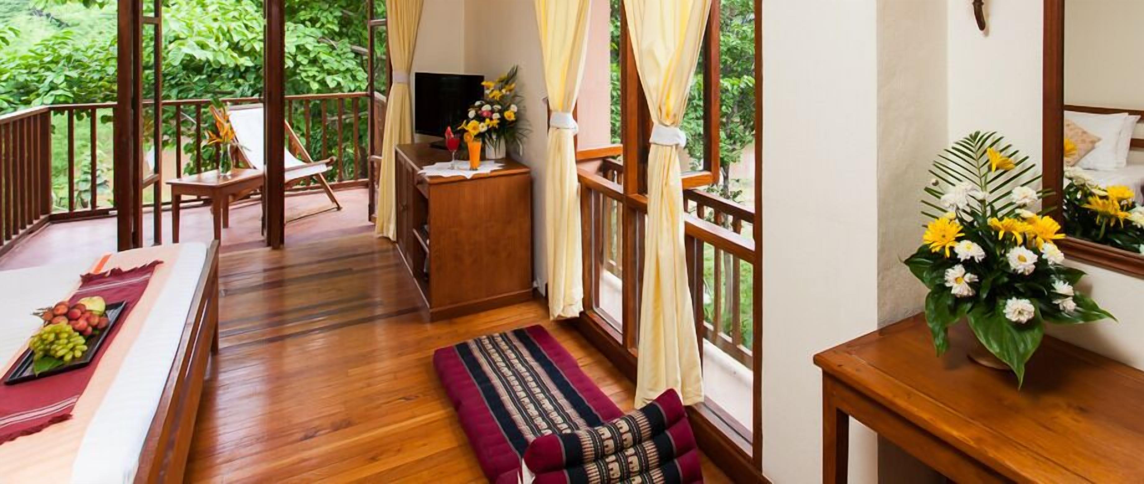 A wooden deck with a sofa, a small table with a vase of flowers, and a TV.