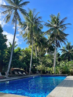 Una piscina al aire libre, tumbonas