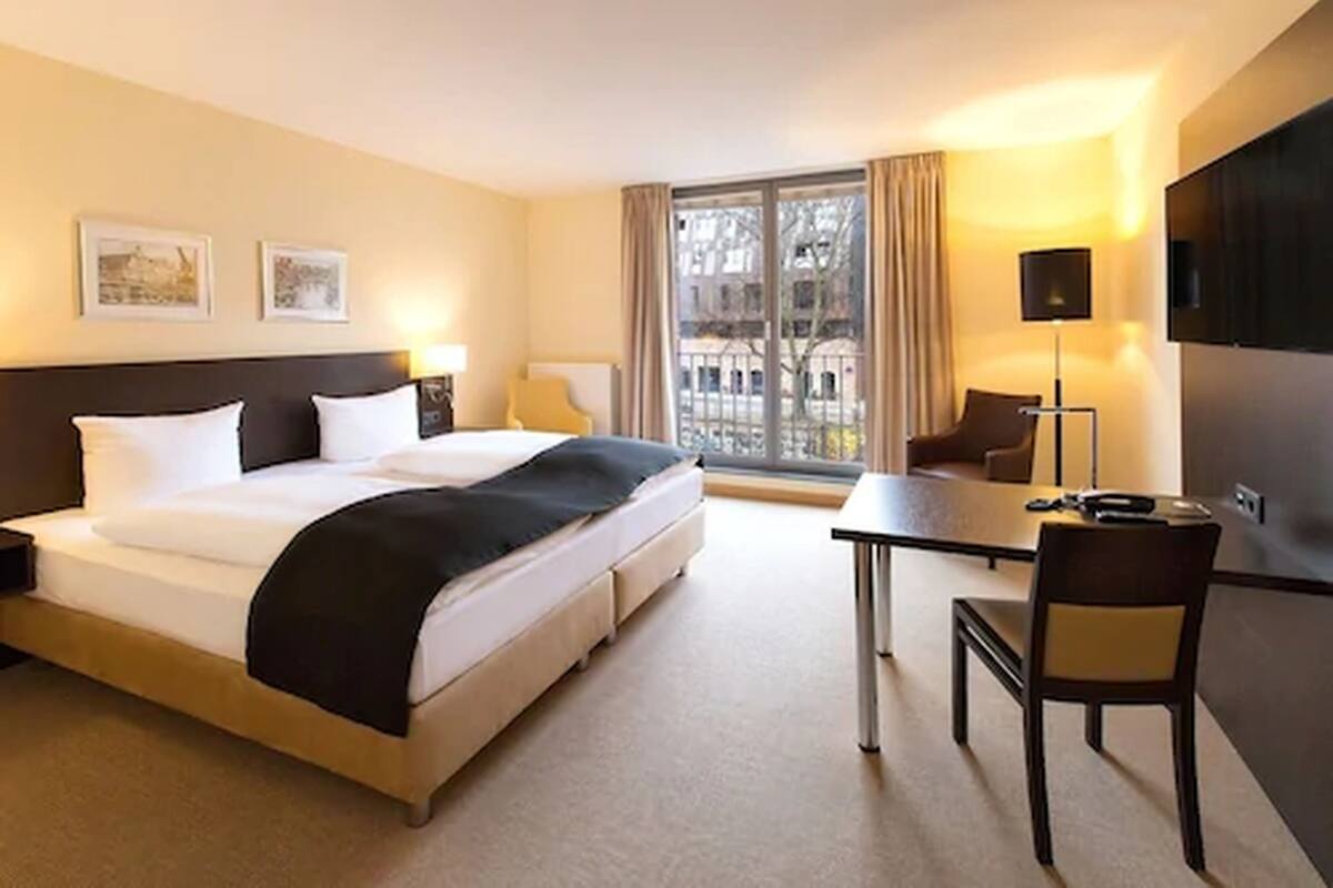 Une chambre d’hôtel avec un grand lit, un bureau, une chaise et un téléviseur.