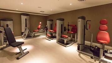 Een sportschool met diverse fitnessapparaten, waaronder een bankdrukpers en een squat rek.