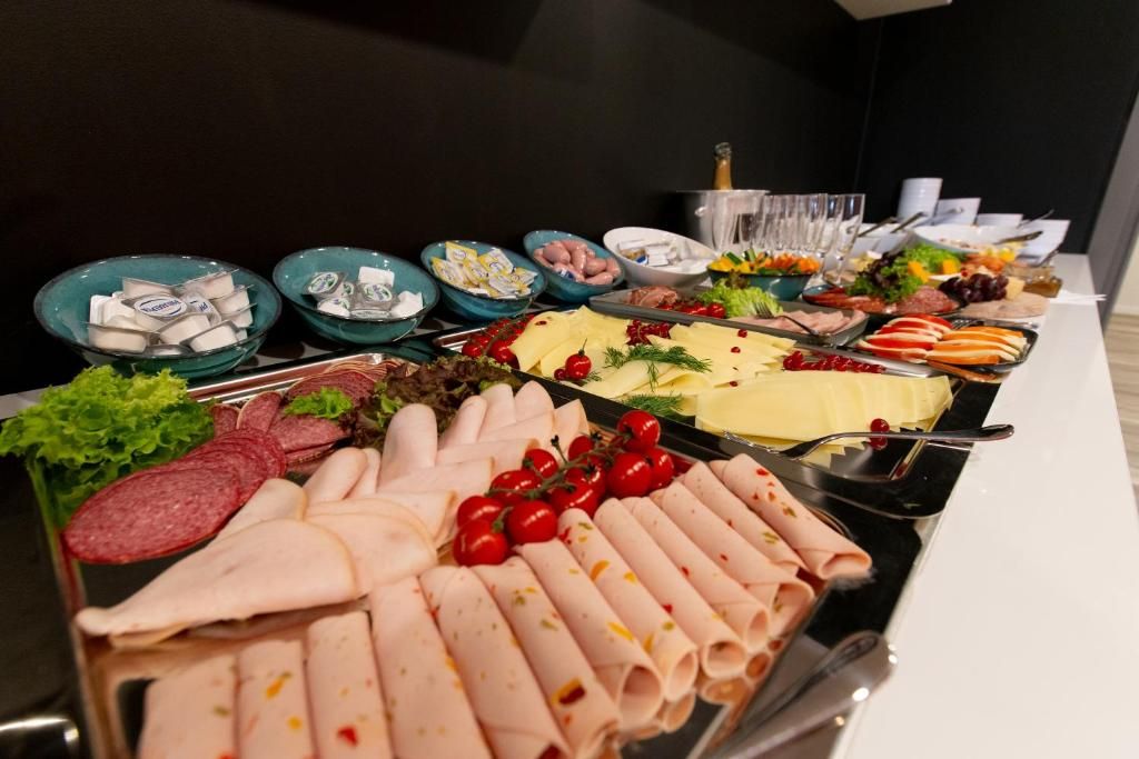 A buffet with various food items including meats, cheeses, and fruits.