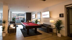 A modern hotel room with a pool table, a sofa, and a view of the city. - DORMERO Hotel Altes Kaufhaus Lüneburg (Lueneburg)