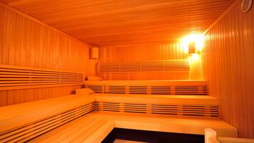 Una sauna con bancos de madera y una lámpara fijada a la pared.