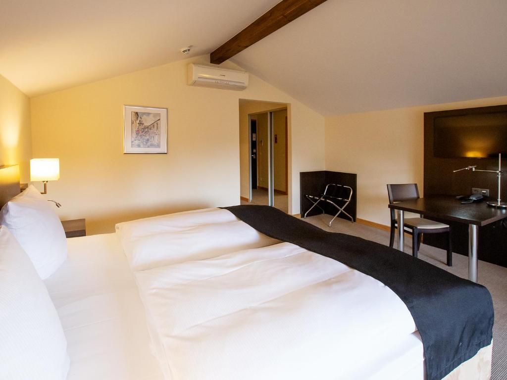 Una camera d'albergo con un letto grande, una scrivania, una sedia e una televisione a schermo piatto.