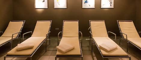 A waiting area with six reclining chairs, a wall-mounted light fixture, and four framed artworks.