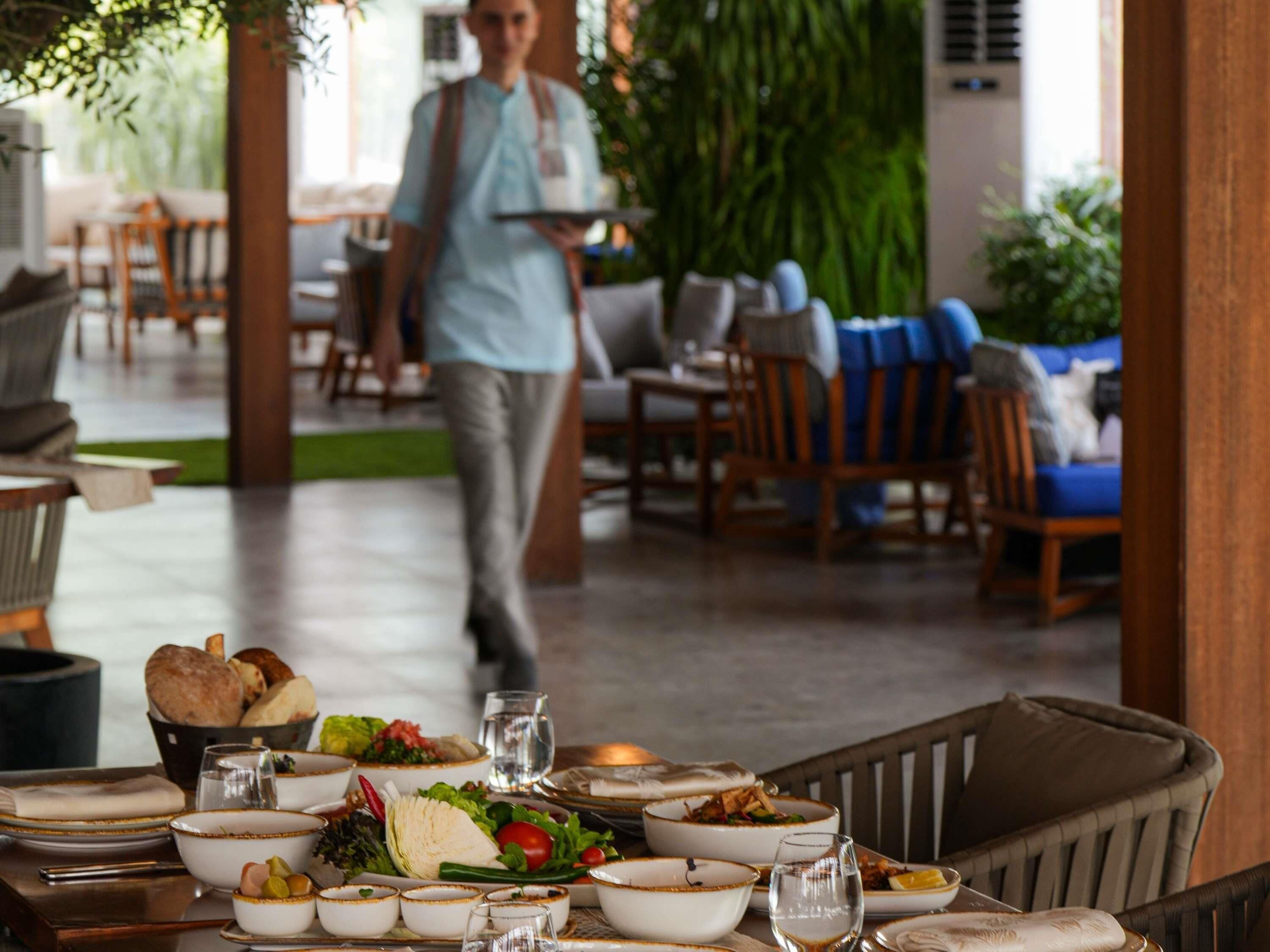 A restaurant setting with a table set for dining, including plates, bowls, and glasses.