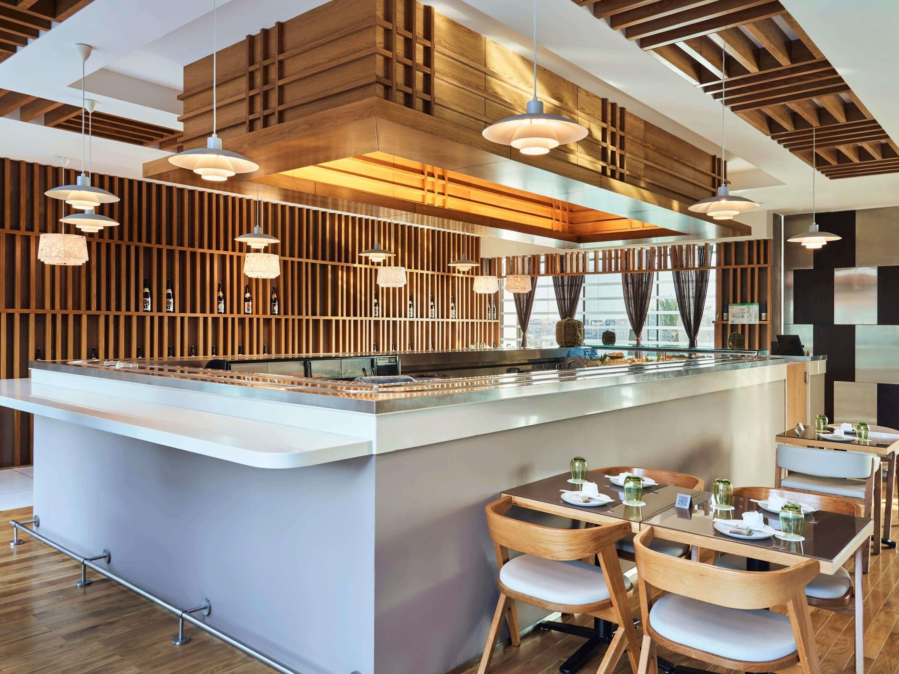 A modern bar area with wooden paneling, pendant lighting, and a central bar counter.