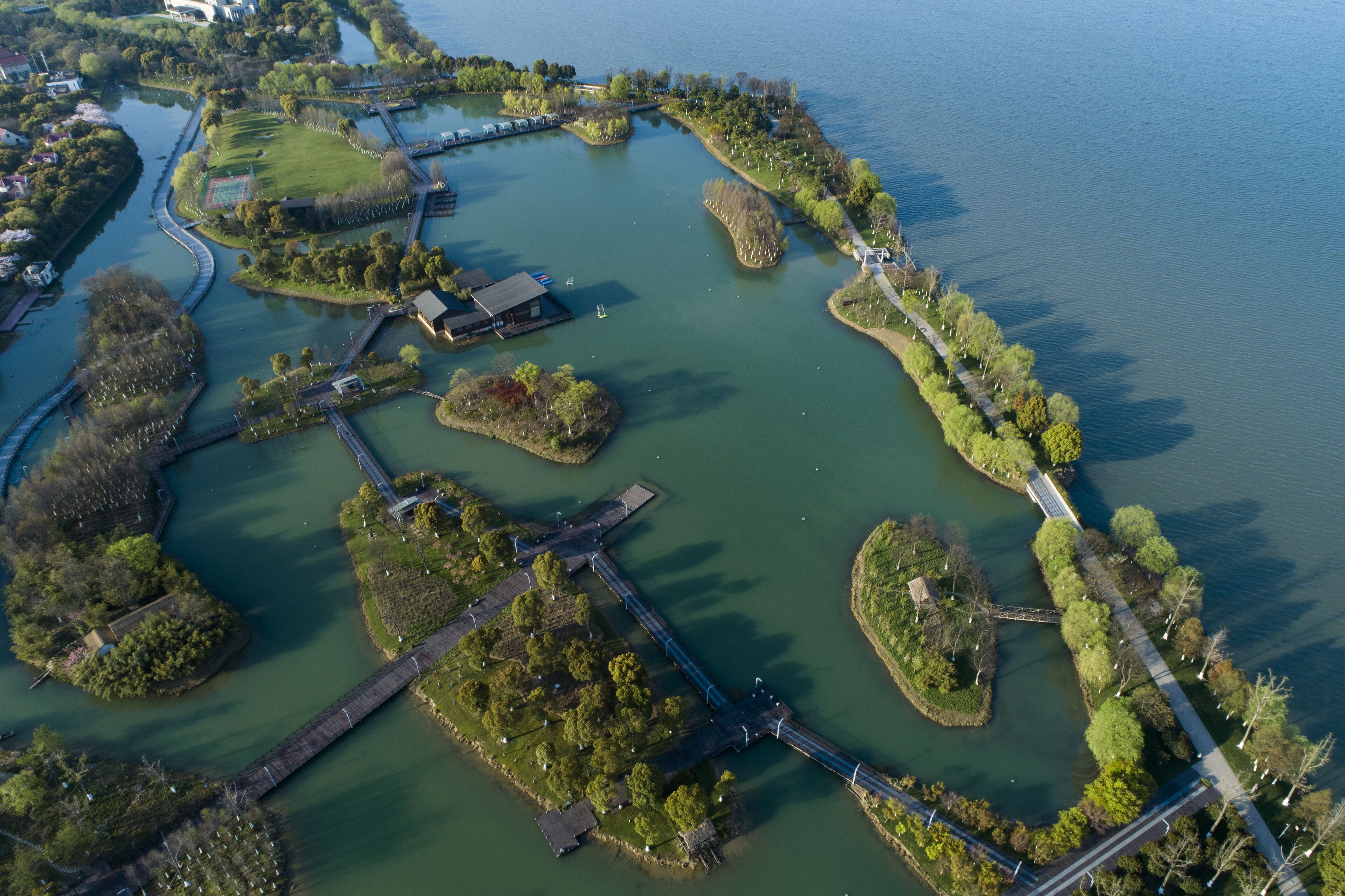 An aerial view of a park with a bridge, pathways, and water bodies.