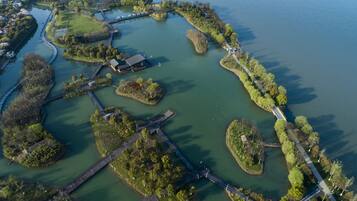 An aerial view of a park with a bridge, pathways, and water bodies.