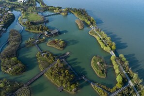 An aerial view of a park with a bridge, pathways, and water bodies. - Fairmont Yangcheng Lake (Suzhou)