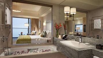 A modern hotel bathroom with a large bathtub, a marble sink, and a large mirror.