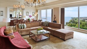 A spacious living room with a large sectional sofa, a glass coffee table, and a chandelier. A dining area with a table and chairs is visible in the background. - Fairmont Yangcheng Lake (Suzhou)