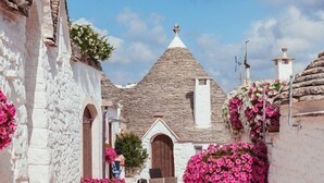 A traditional stone building with a steeply pitched roof, arched doorways, and a central entrance. - Hotel Resort Corte Di Ferro (Carovigno)