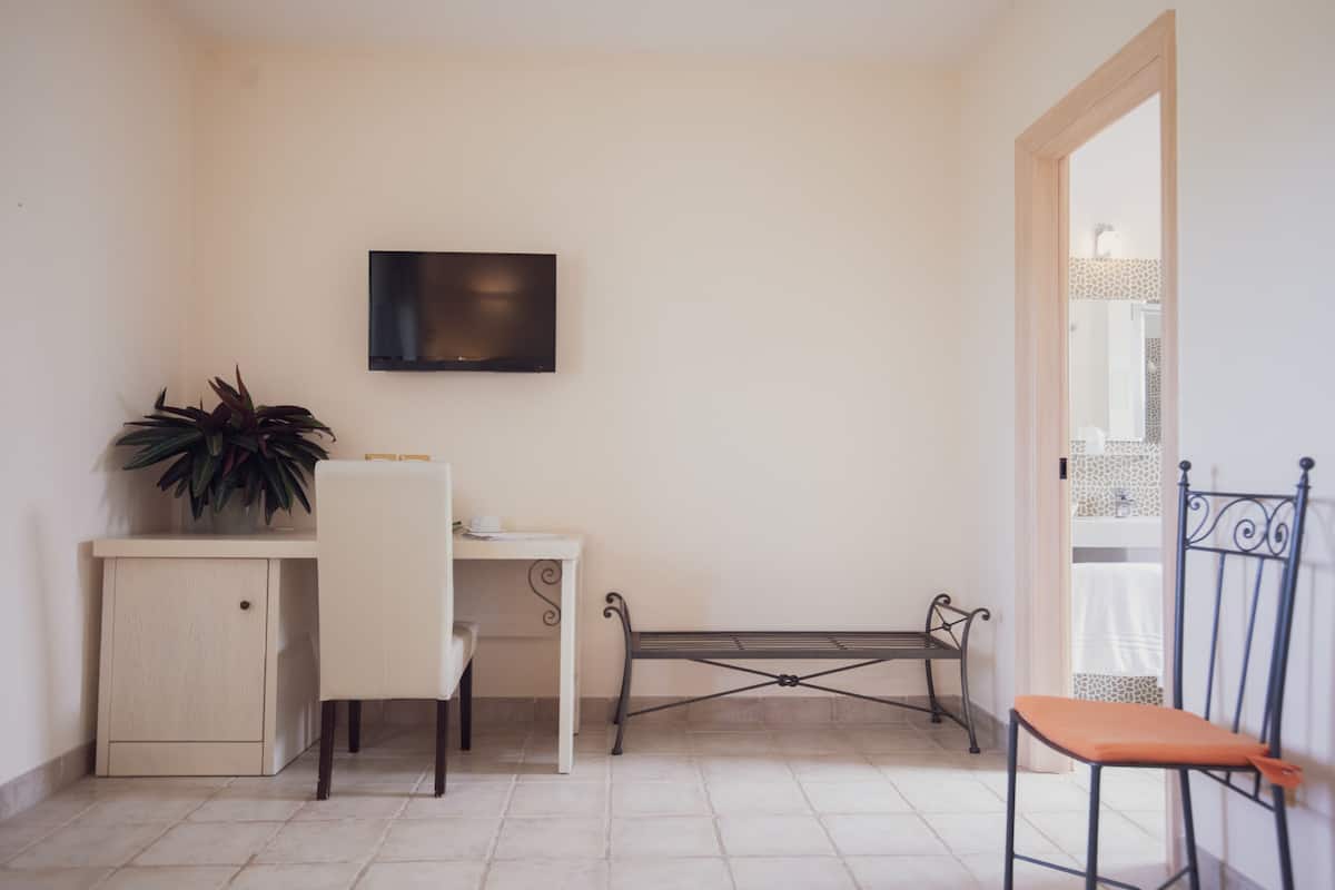 A small room with a desk, chair, and a TV mounted on the wall.