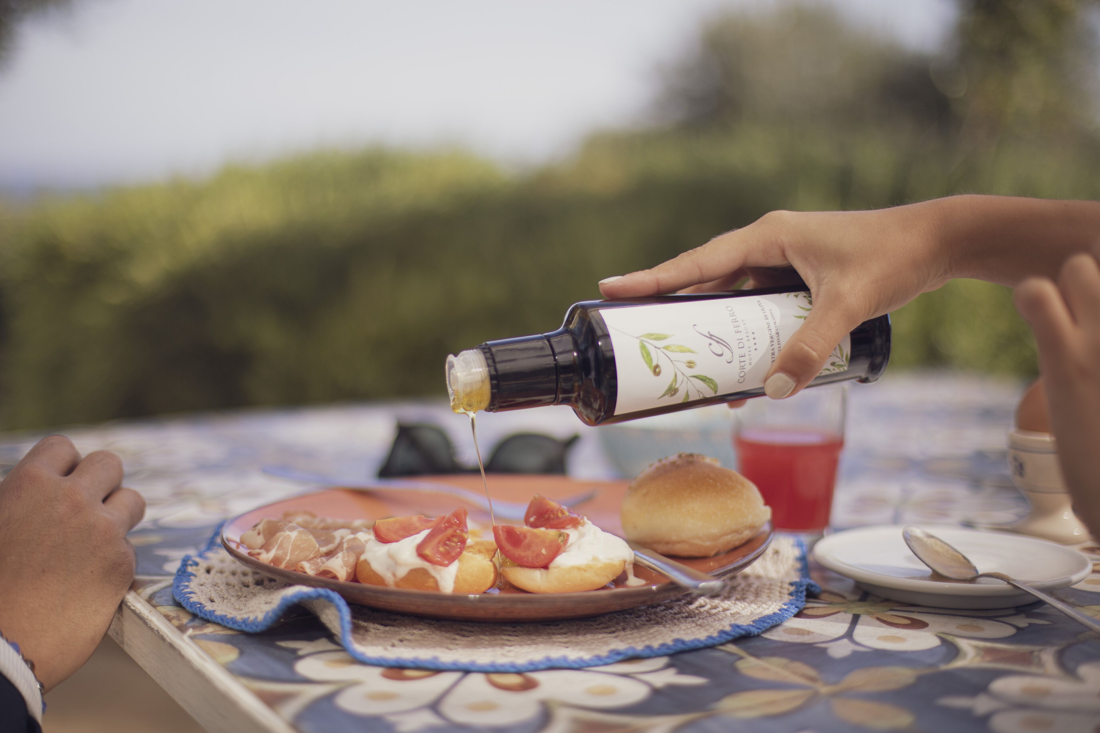 A person pouring a bottle of olive oil over a plate of food.