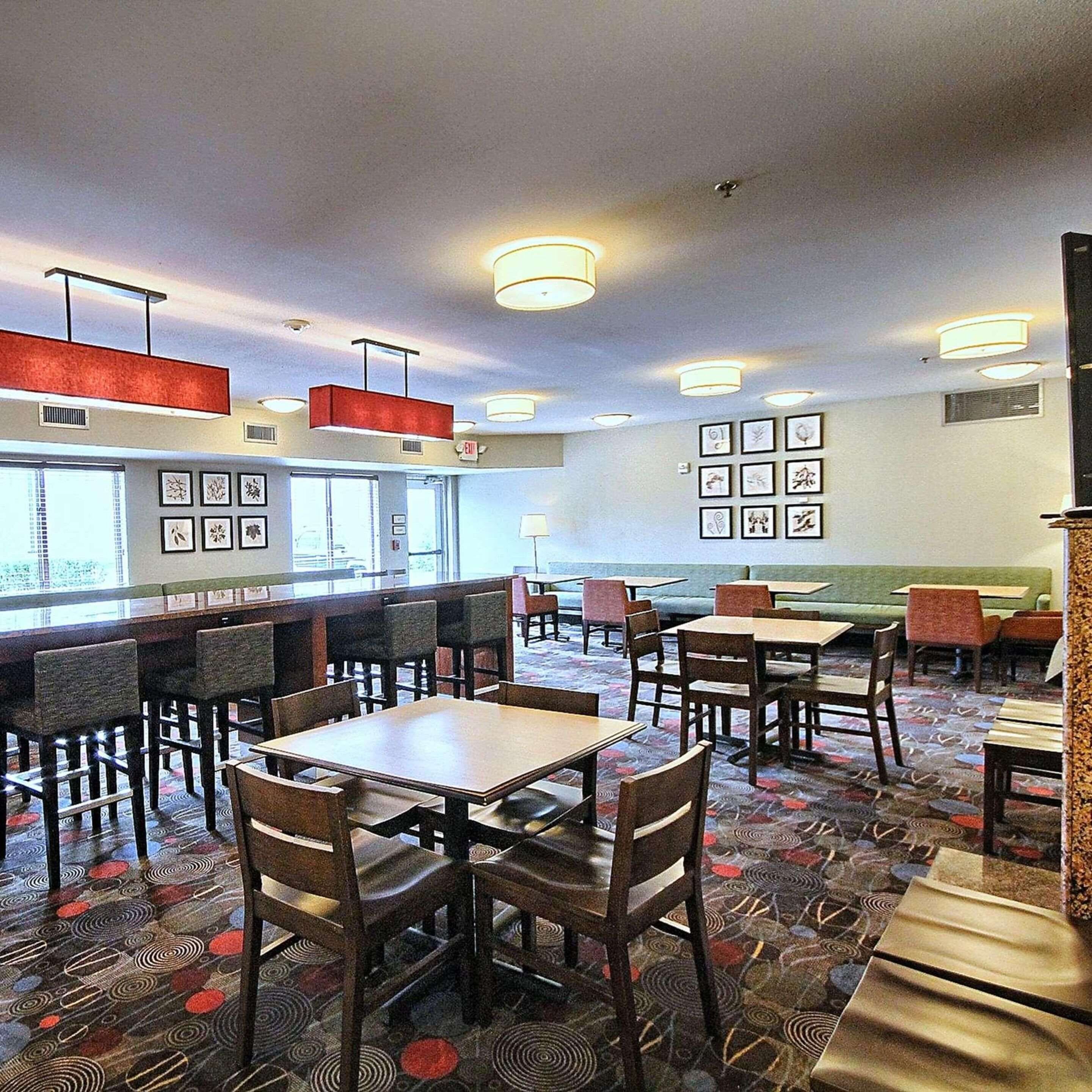 A restaurant with booths and tables, framed artwork on the walls, and a patterned carpet.