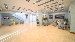 A spacious lobby with a staircase, wicker furniture, and ceiling lights. - Sinclairs Siliguri (Siliguri)