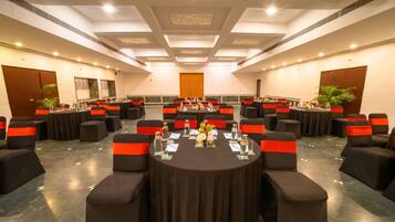 A conference room with round tables, black chairs with red sashes, and a polished marble floor.