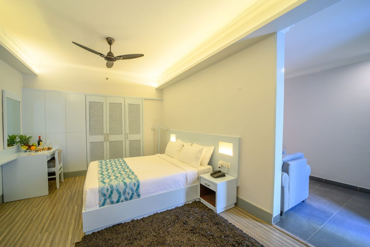 A bedroom with a bed, bedside tables, a desk, and a ceiling fan.