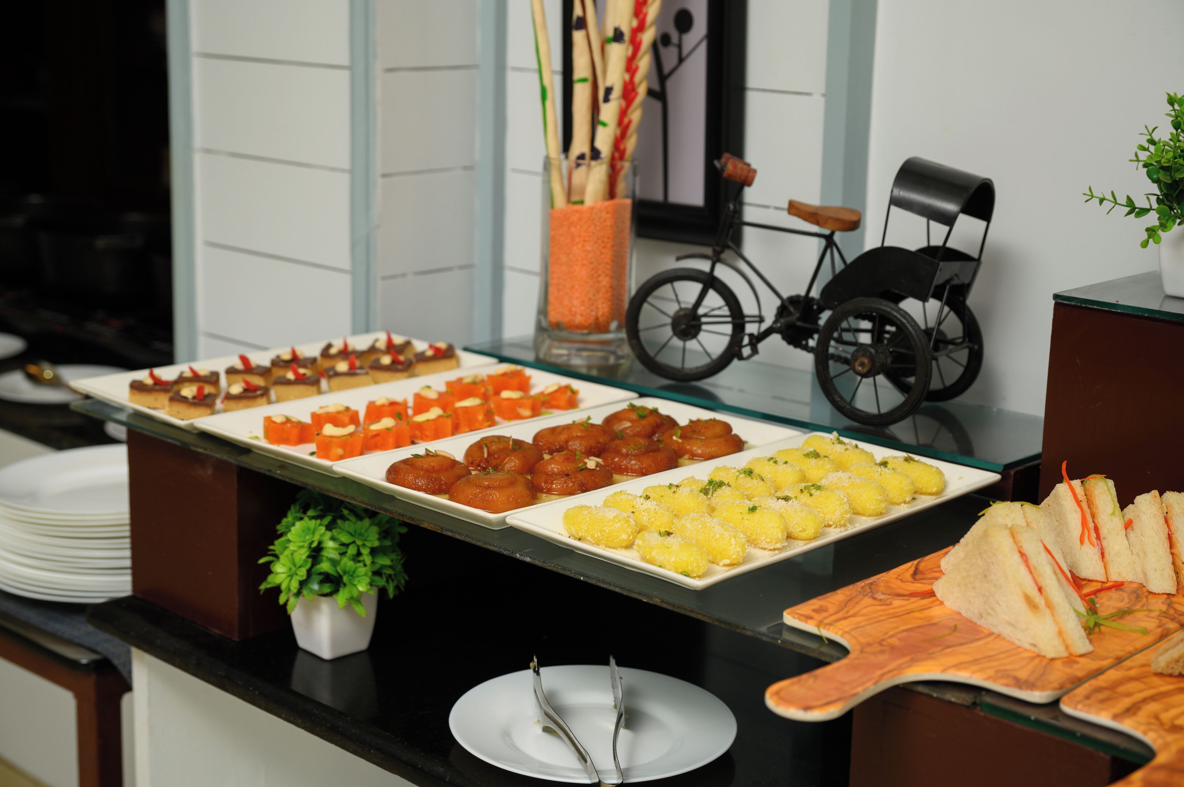 A buffet table with various food items, a bicycle, and a small plant.