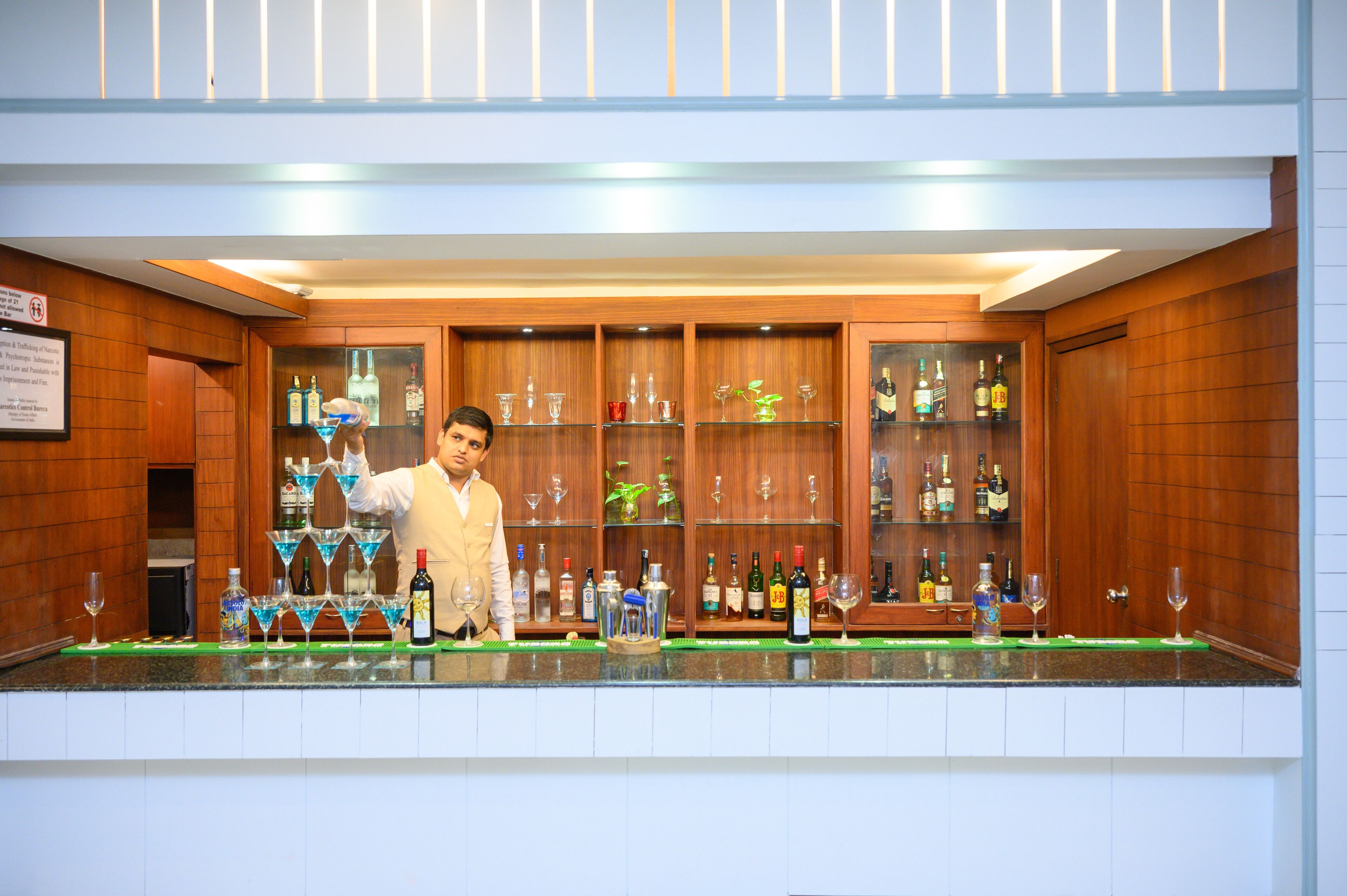 Una zona de bar con estantes de madera llenos de botellas y vasos.
