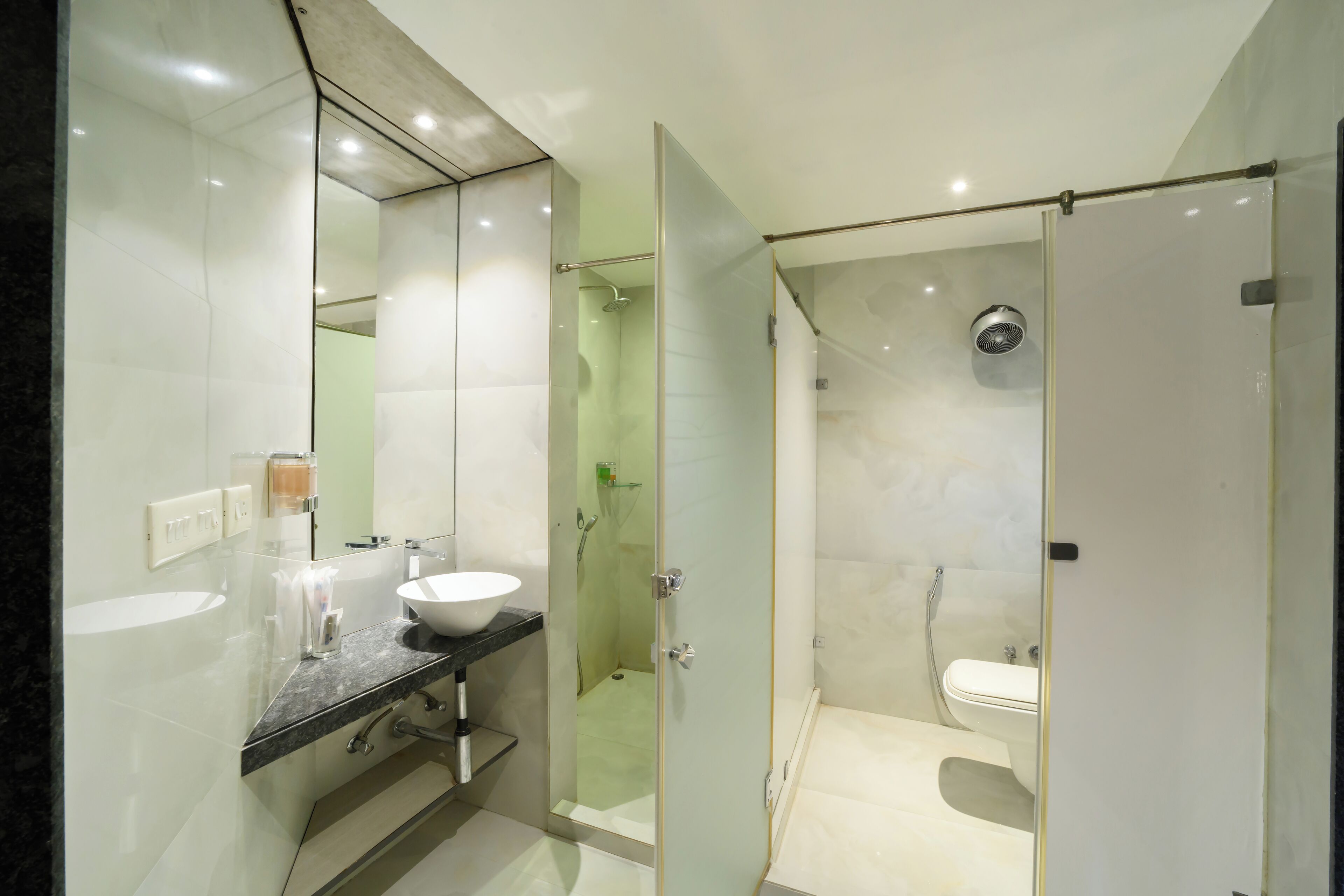 A modern bathroom with a glass-enclosed shower, a white sink, and a large mirror.