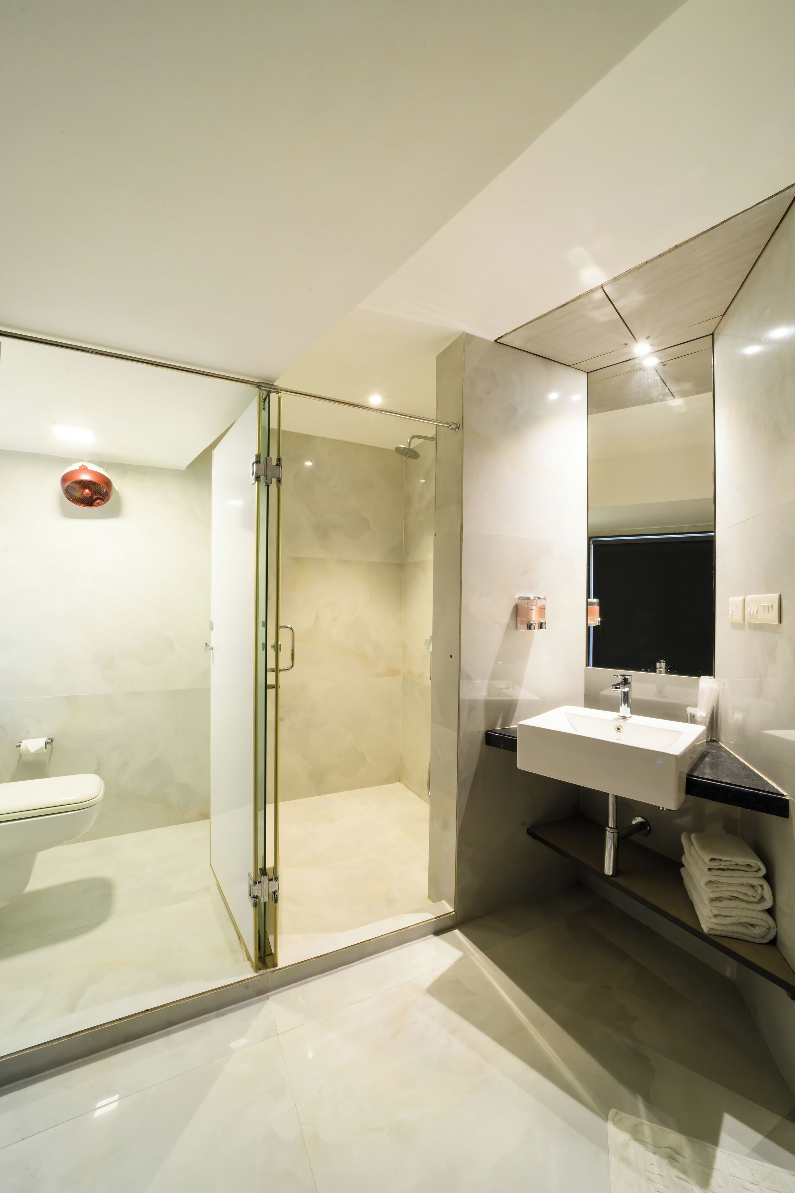 Une salle de bain moderne avec une douche à parois de verre, un lavabo blanc et un grand miroir.