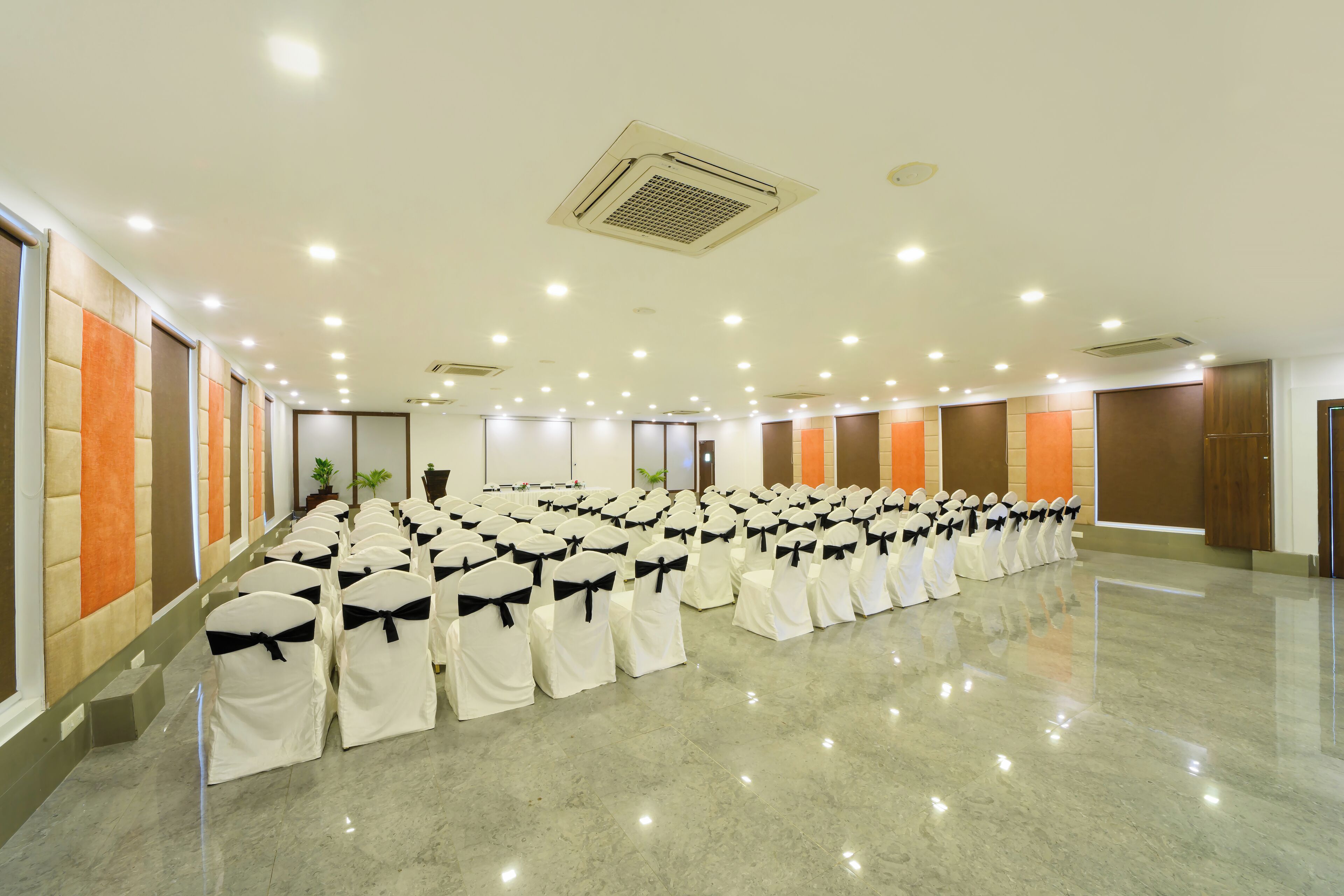 A spacious hall with rows of chairs covered in white and black sashes, arranged for an event.