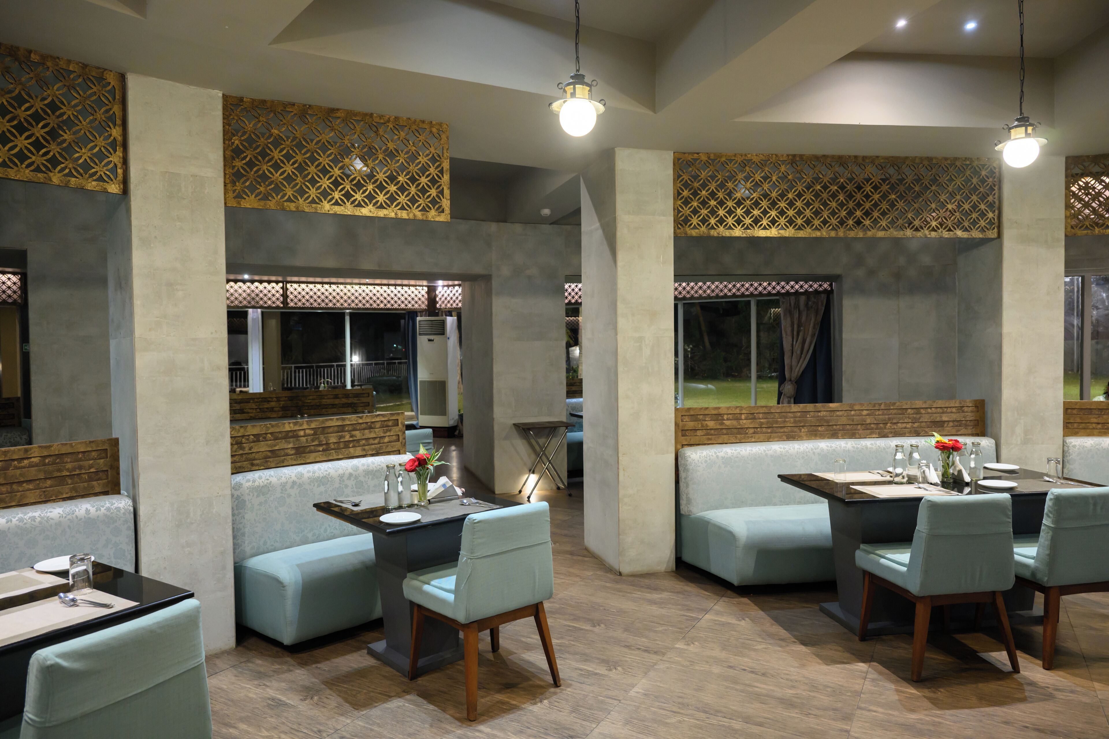 Un restaurant moderne avec un intérieur à la fois élégant et chaleureux, caractérisé par de hauts plafonds, des murs en briques apparentes et une variété de types de sièges, notamment des banquettes et des tables.