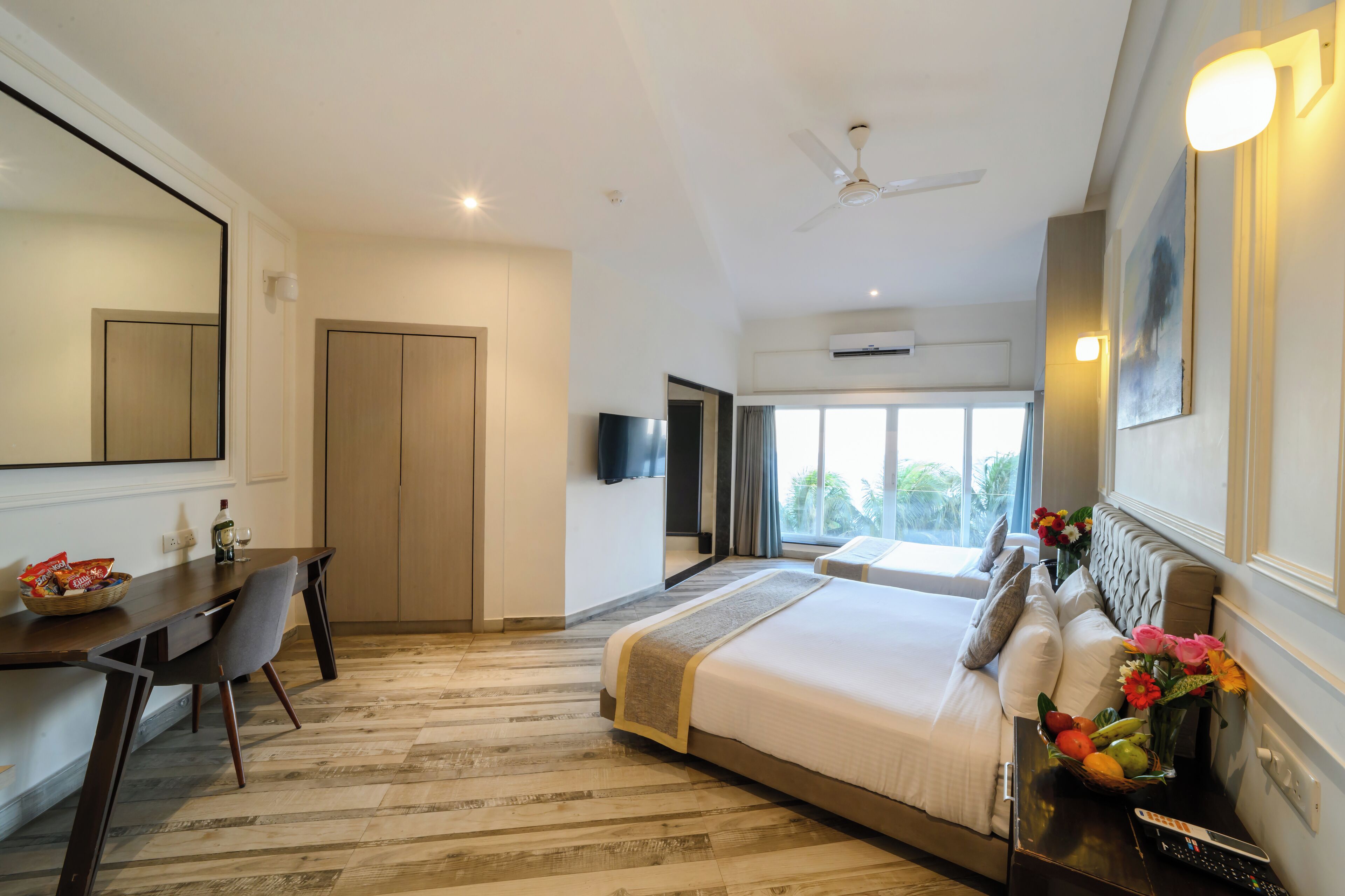 A hotel room with a bed, a desk, a chair, a television, and a window with a view.