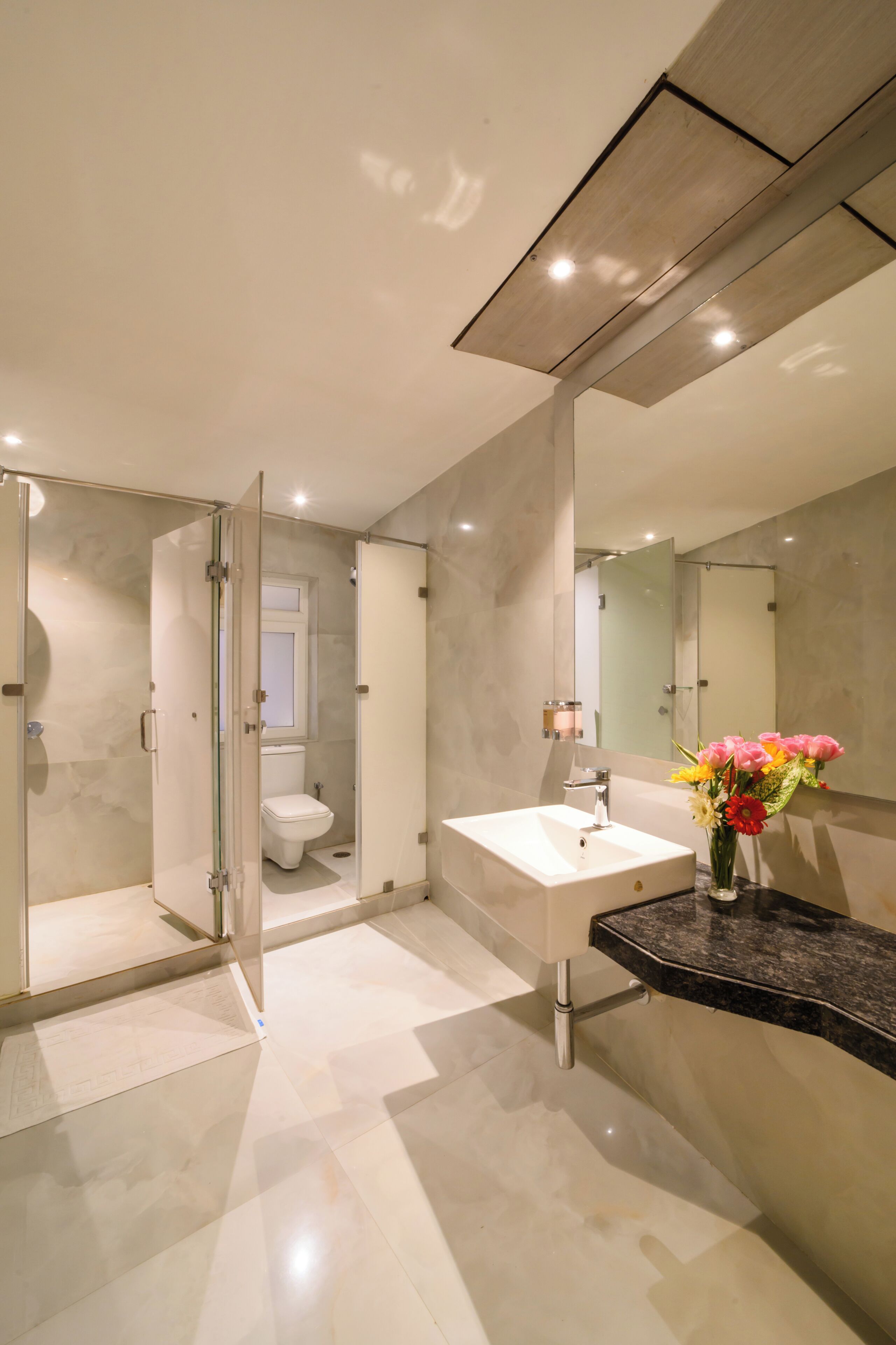 A modern bathroom with a glass shower enclosure, a white sink, and a mirror.