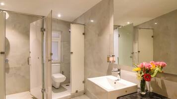A modern bathroom with a glass shower enclosure, a white sink, and a mirror.
