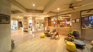 Um hall amplo com piso de madeira, áreas de estar e um balcão de recepção.