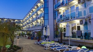 Ein mehrstöckiges Hotel mit Balkonen, Sitzgelegenheiten im Freien und Liegestühlen.
