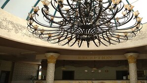 Ein prächtiger Kronleuchter in einer Lobby mit Empfangsschalter und Säulen.
