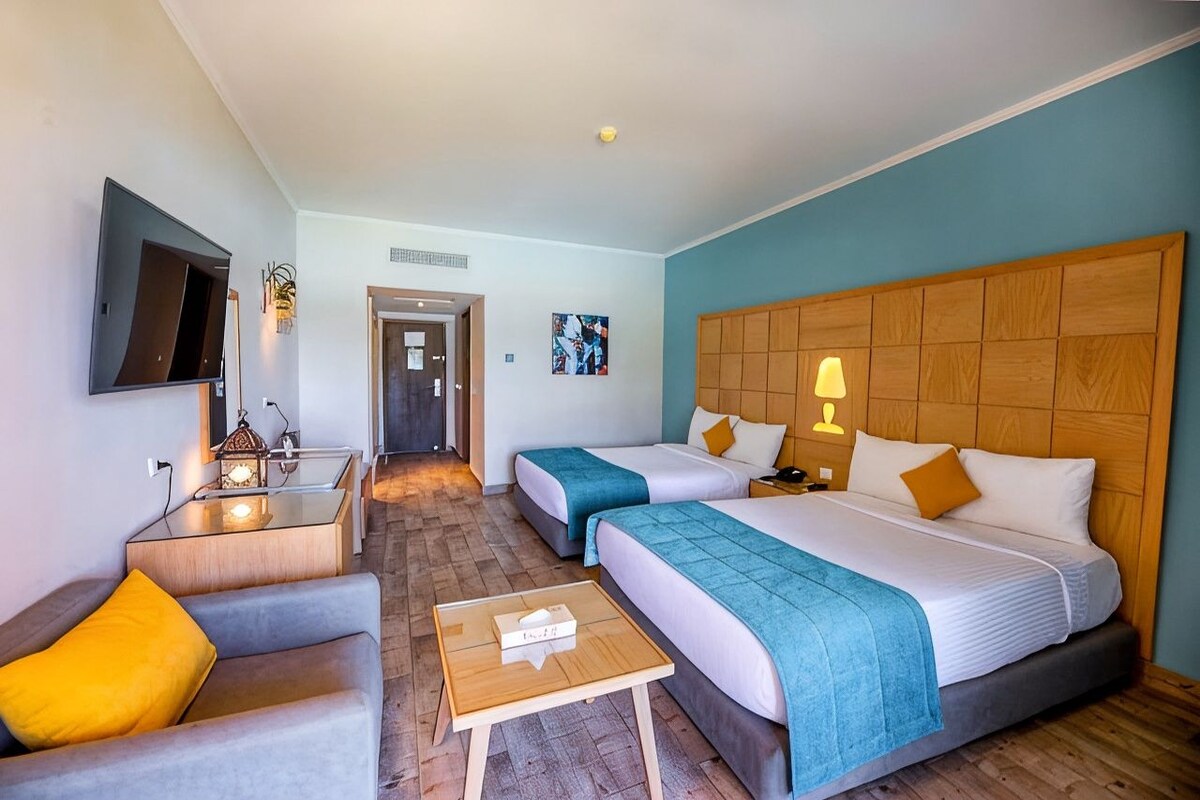 A hotel room with two beds, a TV, a desk, and a chair.