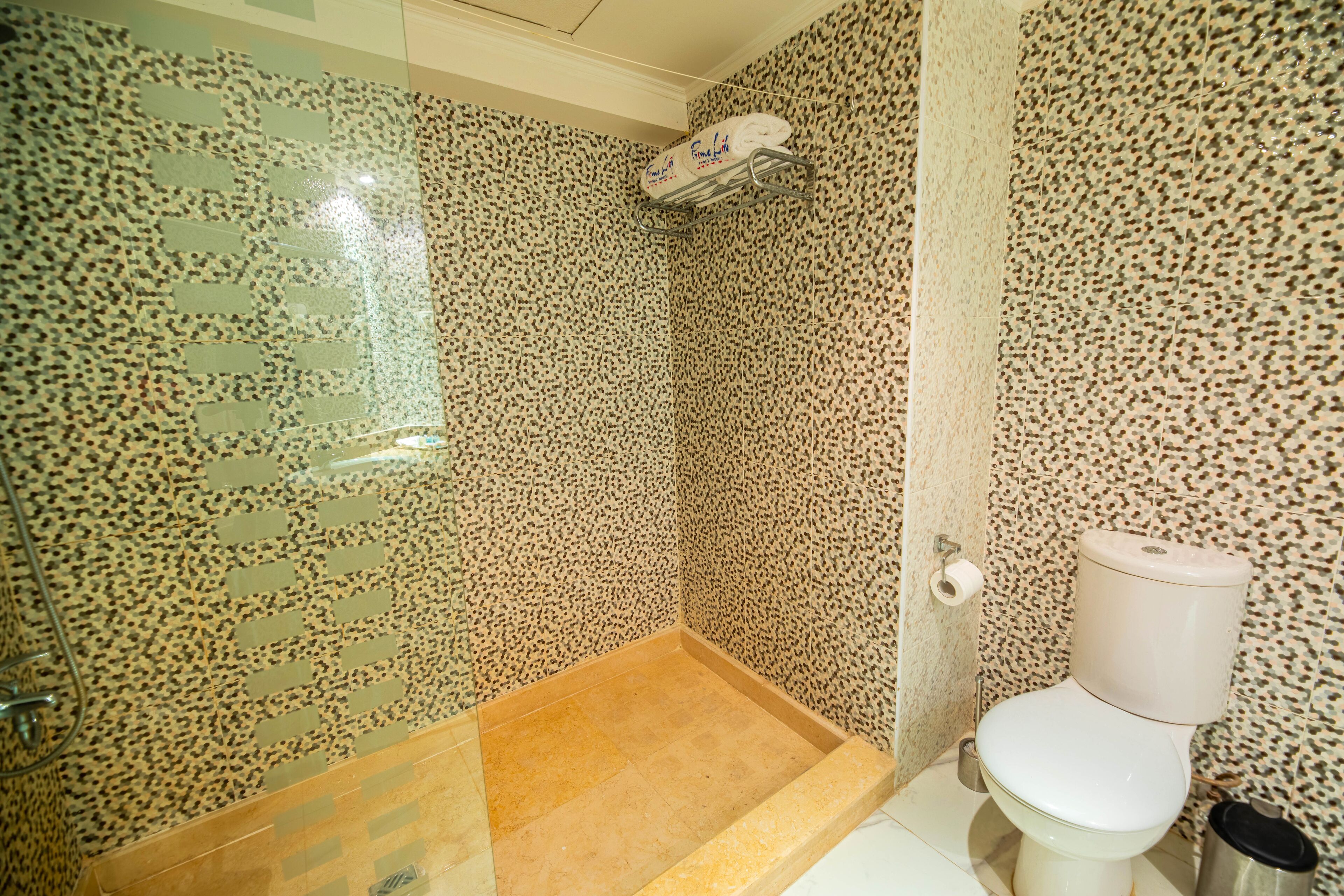 Ein Badezimmer mit Dusche, Toilette und einer Wand mit Muster.