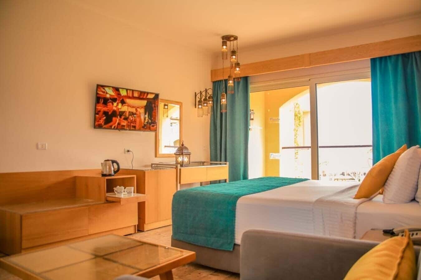 Habitación de hotel con cama, zona de estar, mesa y ventana con cortinas.