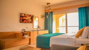 Habitación de hotel con cama, zona de estar, mesa y ventana con cortinas.