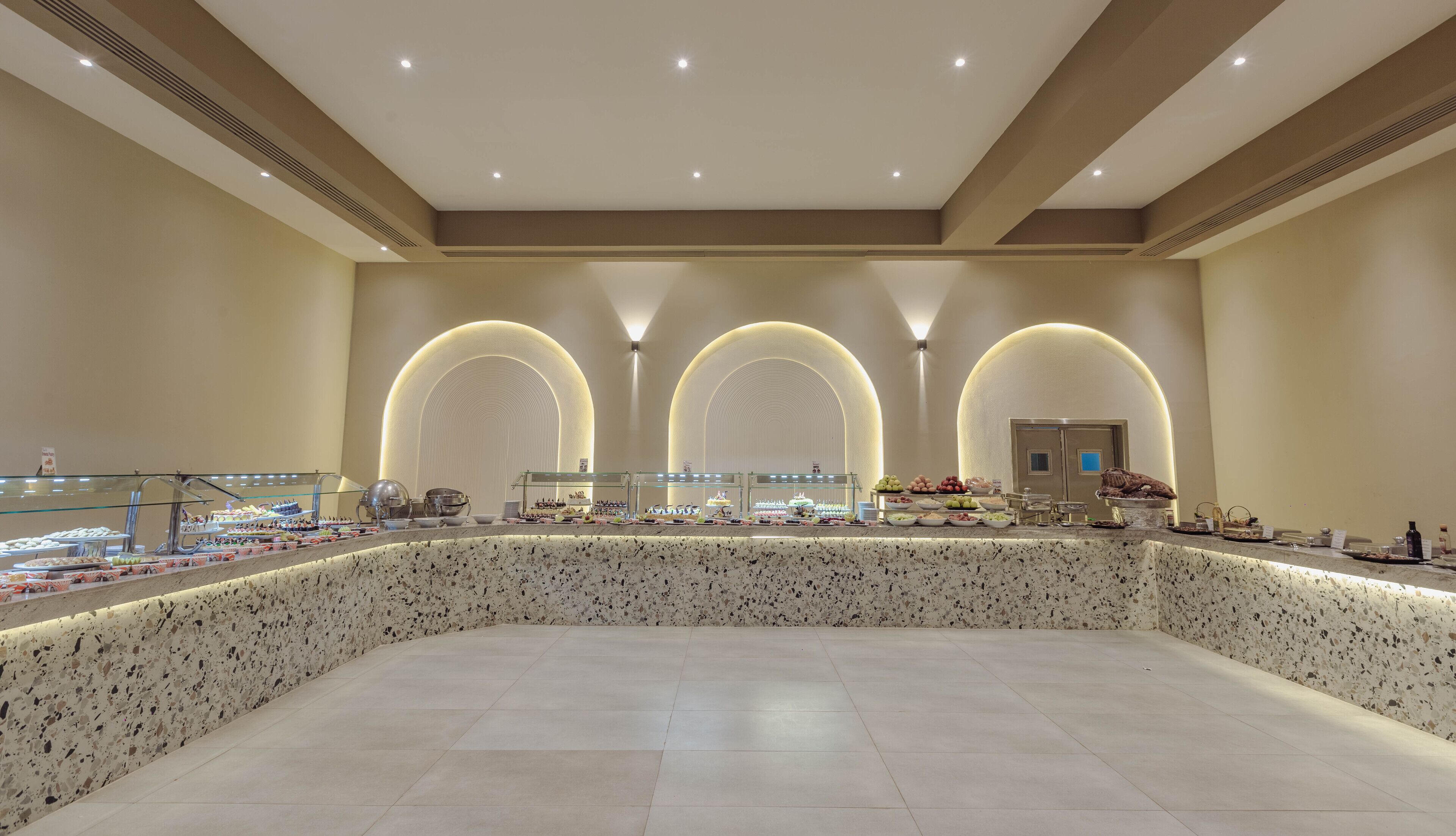A spacious, modern interior with a central island displaying various food items and a seating area.