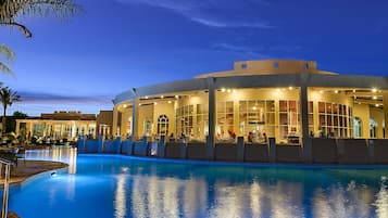 Ein Hotel mit Pool, Außenbereich und einem großen Gebäude mit vielen Fenstern.