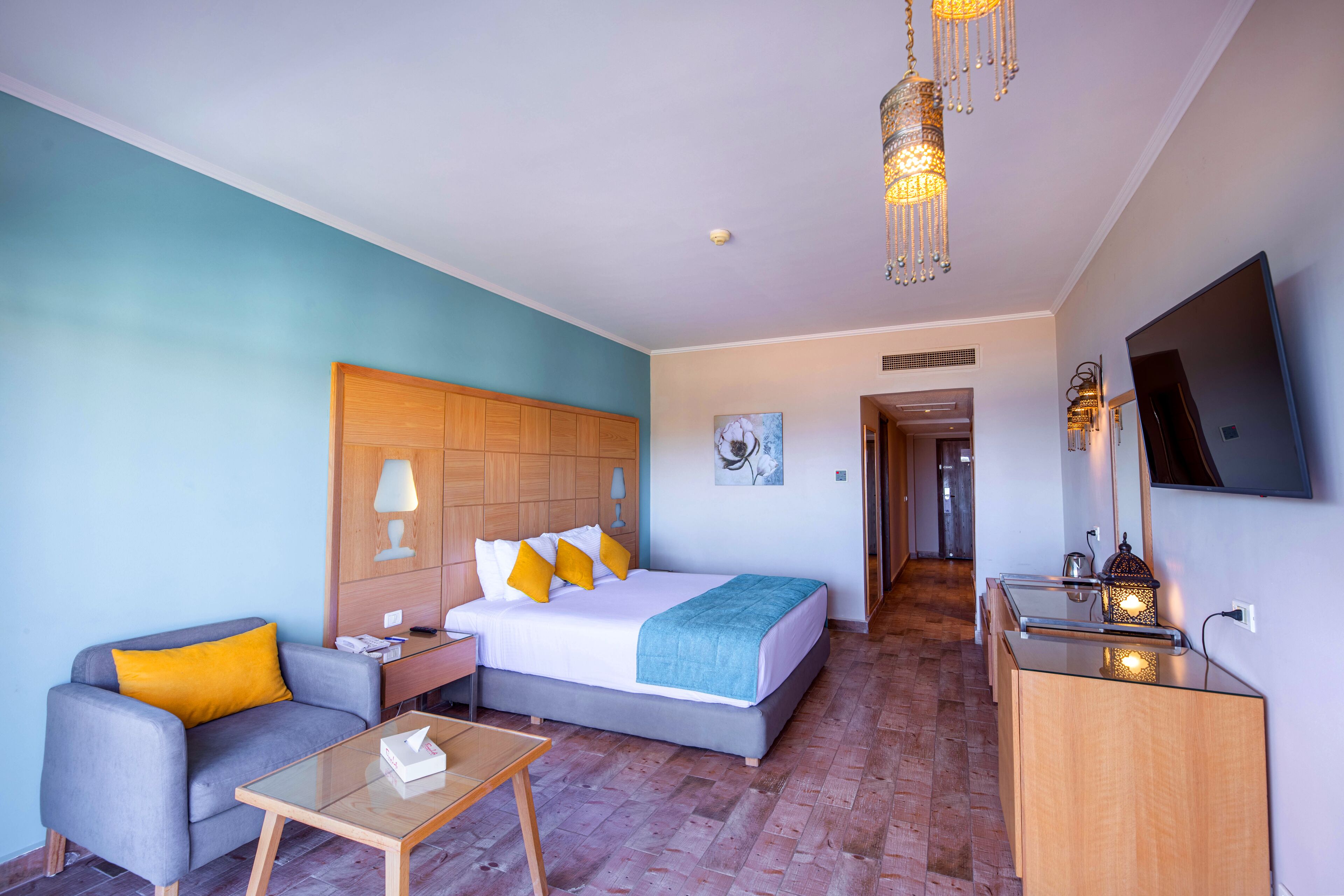 A hotel room with a bed, a sofa, a desk, and a TV.