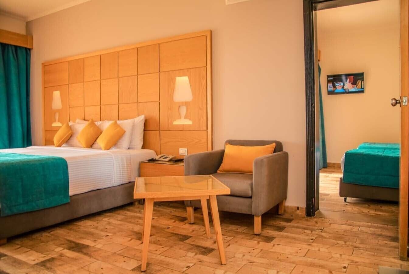A hotel room with a large bed, a desk, a chair, and a second bed.