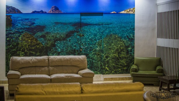 Una habitación con un gran mural de paisaje costero, dos sofás y una mesita de madera.