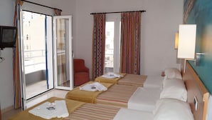 Habitación de hotel con dos camas, televisión, una silla y balcón con cortinas.