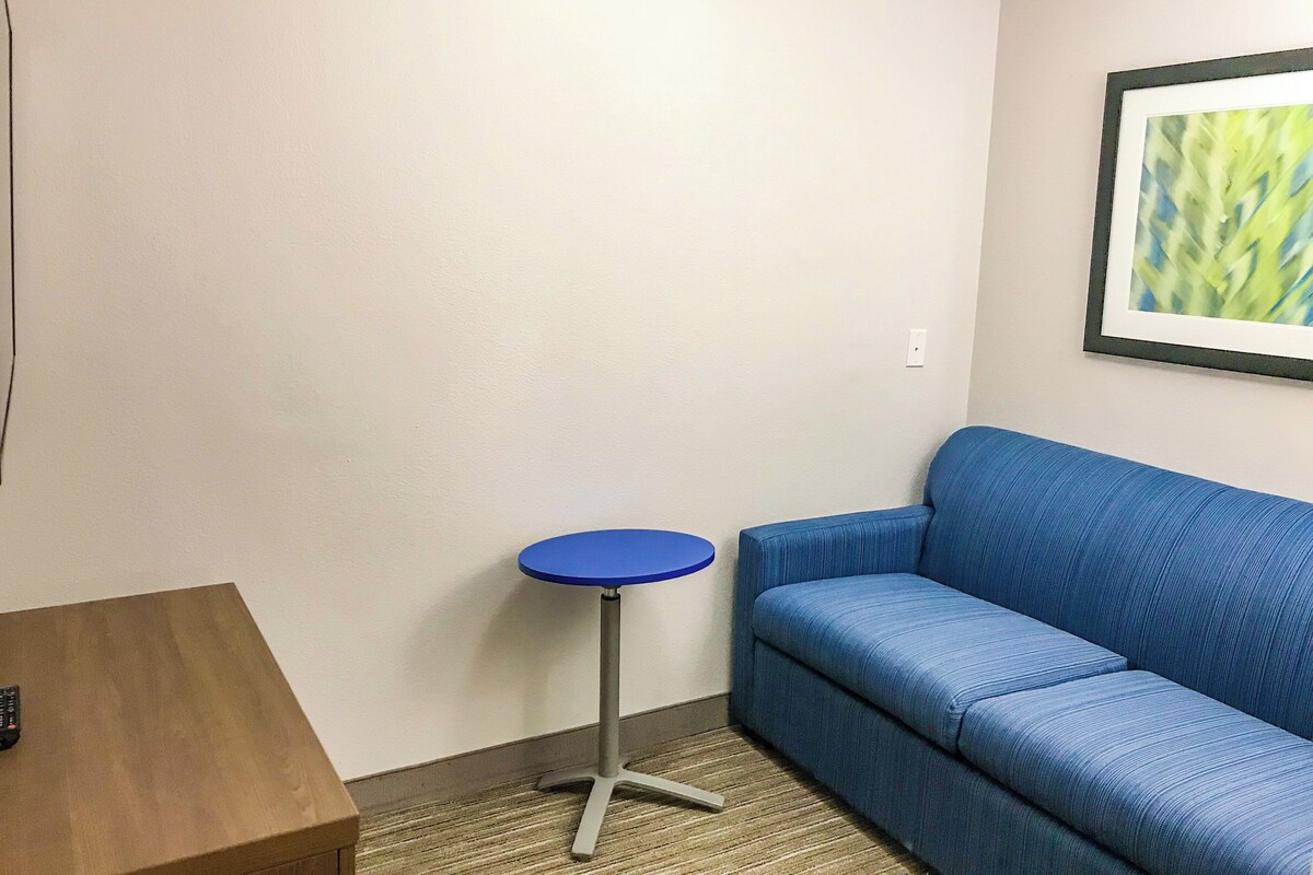 A room with a blue sofa, a small round table, and a framed picture on the wall.
